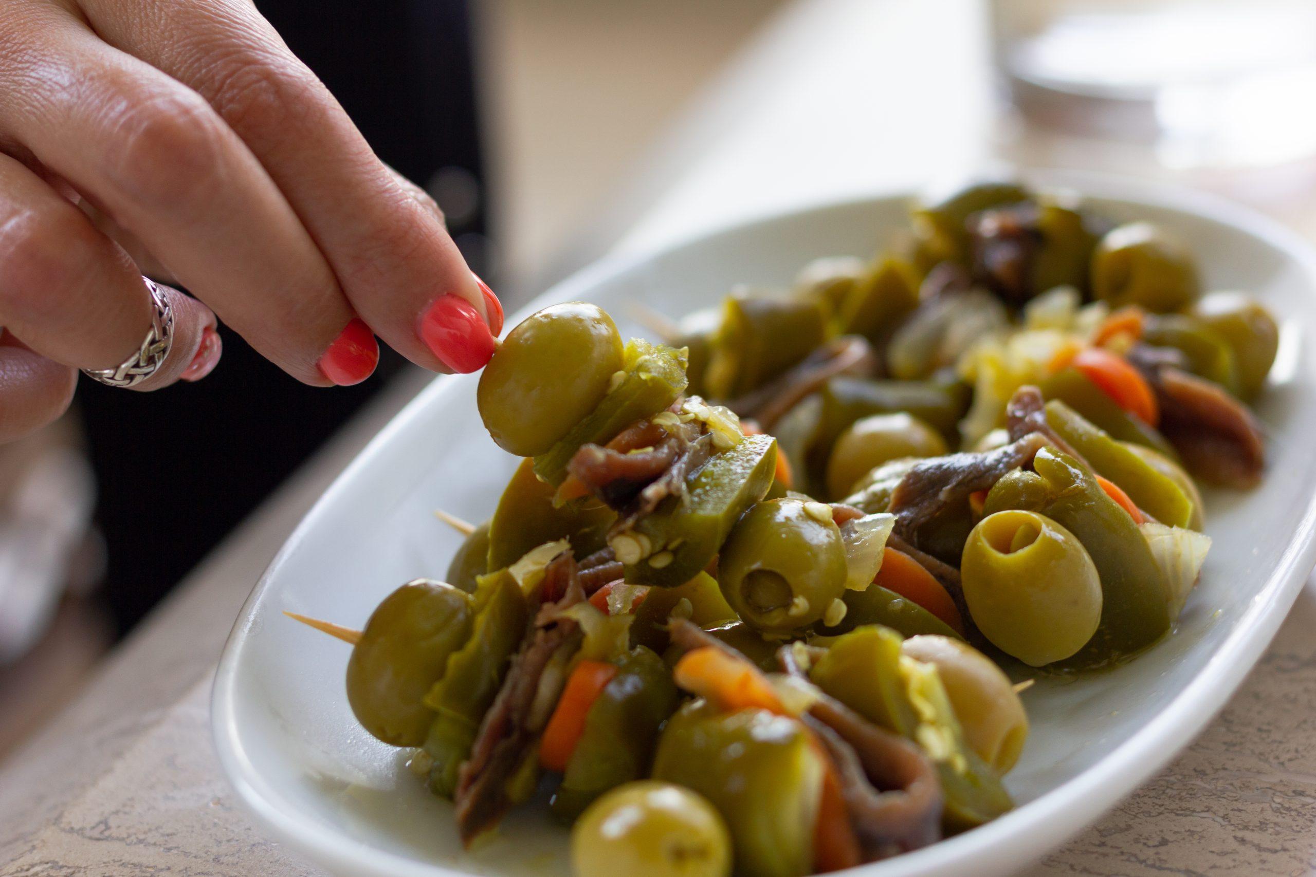 Person Picking Up Olives from a Plate