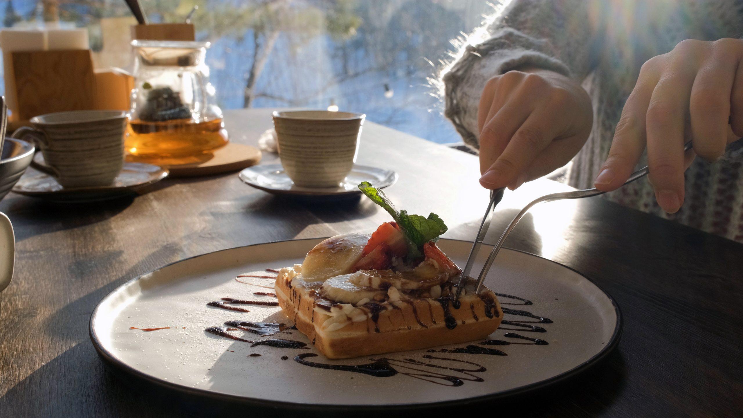 Person Enjoying Dessert with Drinks and Tableware at a Brunch Setting